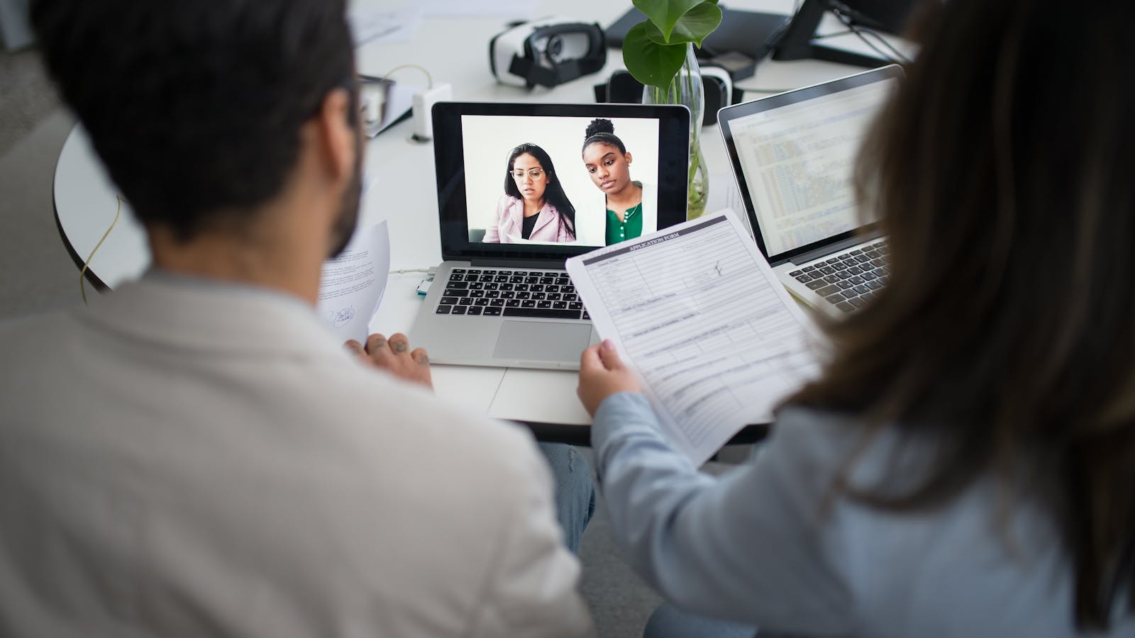 A senior recruiter on a video call with a hiring manager, briefcase and notebook on the desk