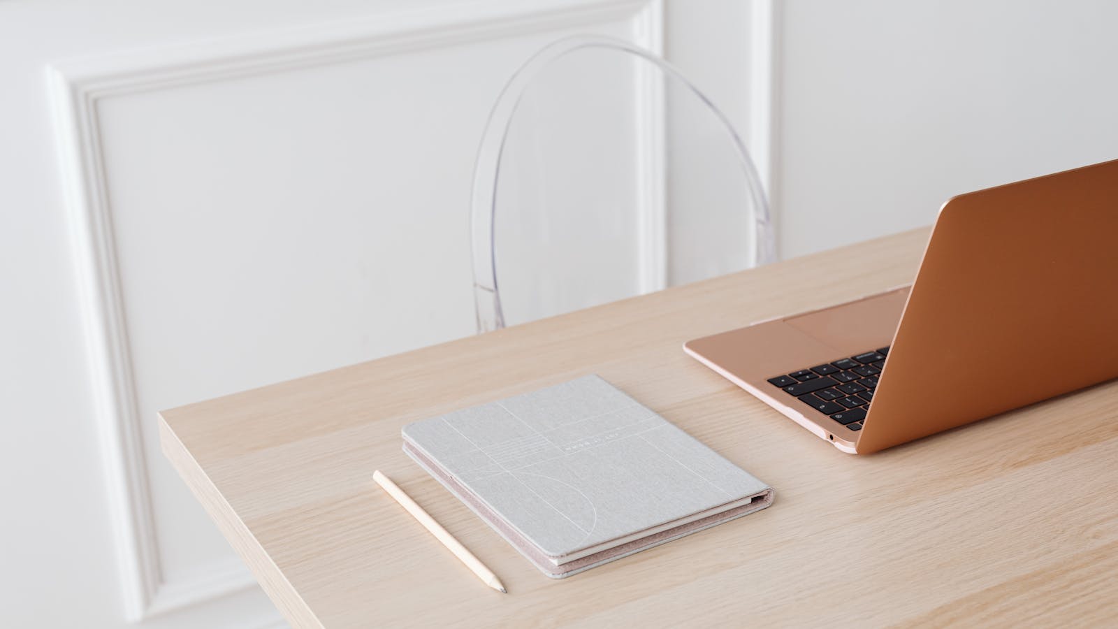 A SaaS founder at a clean desk, laptop and notebook open, looking thoughtful
